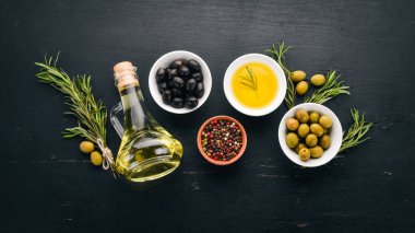 Zeytin ve zeytin yağı ve biberiye kümesi. Yeşil zeytin ve zeytin. Siyah ahşap arka plan üzerinde. Metin için boş alan.