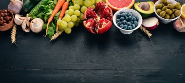 Sağlıklı gıda seçimi yeme temiz: sebze, meyve, fındık, çilek ve mantar, maydanoz, baharatlar. Siyah bir arka plan üzerinde. Metin için boş alan.