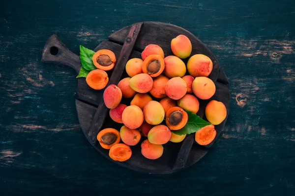 Fresh apricots with leaves On a black wooden background. Top view. Free space for your text.