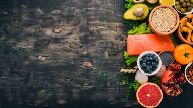 Sağlıklı gıda. Balık, fındık, taze sebze ve meyve. Eski bir ahşap masa üzerinde. Üstten görünüm. Metin için boş alan.