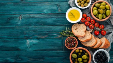 Yeşil zeytin, siyah zeytin ve aperatifler kümesi. Mavi ahşap bir masa üzerinde. Metin için boş alan.