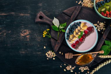 Yoğurt böğürtlen, ahududu ve muz ile. Kalenin içinde. Ahşap bir arka plan üzerinde. Üstten görünüm. Metin için boş alan.