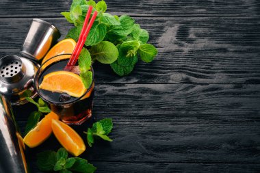 Portakal ve nane ile alkollü kokteyl. Negroni, Long Island, rom-kola. Siyah ahşap arka plan üzerinde. Metin için boş alan.