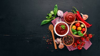 Geleneksel Domates ketçap sosu. Kiraz domates, baharat, biber, zeytin yağı, maydanoz. Üstten görünüm. Siyah ahşap arka plan üzerinde. Boş alan.