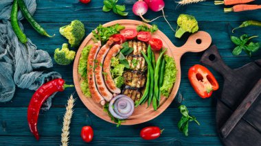 Patlıcan, fasulye ve tahta üzerinde domates ızgara sosis. Sağlıklı gıda. Mavi ahşap bir masa üzerinde. Üstten görünüm. Metin için boş alan.