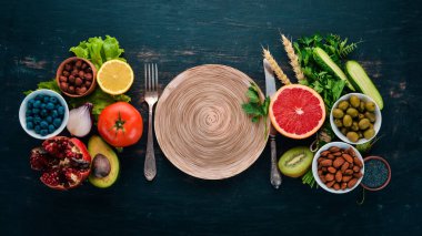 Sağlıklı gıda seçimi yeme temiz: sebze, meyve, fındık, çilek ve mantar, maydanoz, baharatlar. Siyah bir arka plan üzerinde. Metin için boş alan.