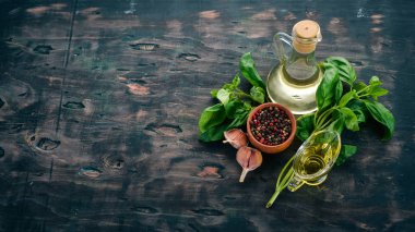 Fesleğen, baharatlar ve zeytin yağı. Üstten görünüm. Ahşap bir arka plan üzerinde. Metin için boş alan.