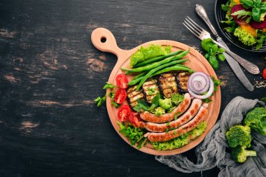 Patlıcan, fasulye ve tahta üzerinde domates ızgara sosis. Sağlıklı gıda. Siyah ahşap bir masa üzerinde. Üstten görünüm. Metin için boş alan.