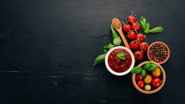 Geleneksel Domates ketçap sosu. Kiraz domates, baharat, biber, zeytin yağı, maydanoz. Üstten görünüm. Siyah ahşap arka plan üzerinde. Boş alan.