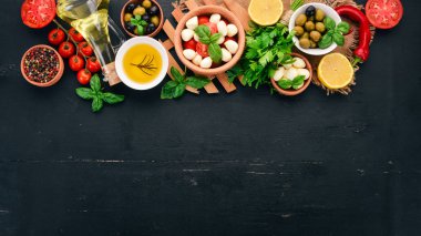 İtalyan caprese salatası için malzemeler. Mozzarella peyniri, kiraz domates, fesleğen yaprağı, zeytin, yağ, karabiber. Siyah ahşap arka plan üzerinde. Metin için boş alan.