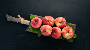 Düz şeftali yeşil siyah bir ahşap arka plan üzerinde bırakır. Üstten görünüm. Metniniz için boş alan.