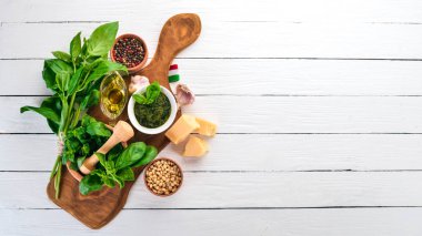 Geleneksel fesleğen pesto sos. Fesleğen, parmesan peyniri, zeytinyağı. Üstten görünüm. Beyaz ahşap zemin üzerinde. Metin için boş alan.