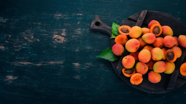 Fresh apricots with leaves On a black wooden background. Top view. Free space for your text.