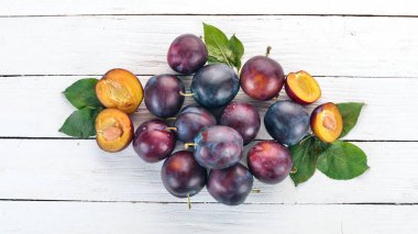 Taze erik yaprakları ile. Meyve. Beyaz ahşap zemin üzerinde. Üstten görünüm. Metniniz için boş alan.