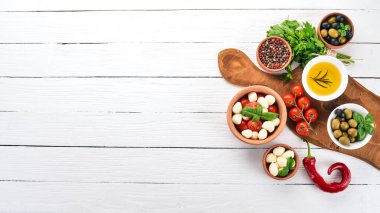 Mozzarella peyniri, domates, fesleğen yaprağı, yağ, zeytin, biber. Beyaz ahşap bir masa üzerinde caprese salatası. Metin için boş alan.