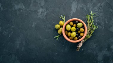 Zeytin tabağı ve biberiye. Taş bir arka plan üzerinde. Metin için boş alan.