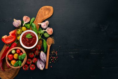 Geleneksel Domates ketçap sosu. Kiraz domates, baharat, biber, zeytin yağı, maydanoz. Üstten görünüm. Siyah ahşap arka plan üzerinde. Boş alan.