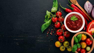 Geleneksel Domates ketçap sosu. Kiraz domates, baharat, biber, zeytin yağı, maydanoz. Üstten görünüm. Siyah ahşap arka plan üzerinde. Boş alan.
