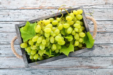Beyaz üzüm mezarda bir beyaz tahta masada. Üzüm yaprakları. Üstten görünüm. Metin için boş alan.