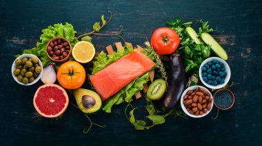 Sağlıklı gıda kümesi. Balık, fındık, protein, meyveler, sebze ve meyve. Siyah ahşap arka plan üzerinde. Üstten görünüm. Metin için boş alan.