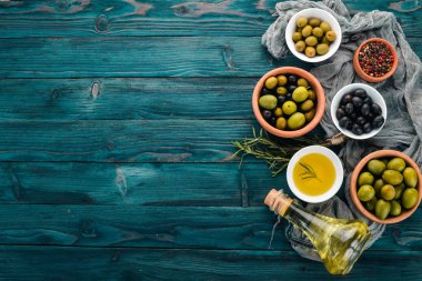Yeşil zeytin, siyah zeytin ve aperatifler kümesi. Mavi ahşap bir masa üzerinde. Metin için boş alan.