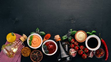 Soslar siyah bir ahşap arka plan ayarla. Ketçap, mayonez, hardal, soya sosu, Barbekü sos, biber ve baharat. Üstten görünüm. Metin için boş alan.