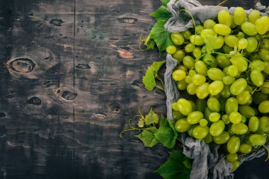 Taze yeşil üzüm üzüm yaprakları ile. Üstten görünüm. Siyah ahşap arka plan üzerinde. Metin için boş alan.