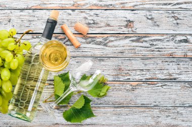 Bir şişe şarap gözlük ve üzüm. Üzüm yaprakları. Üstten görünüm. Beyaz ahşap zemin üzerinde. Metin için boş alan.