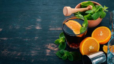 Portakal ve nane ile alkollü kokteyl. Negroni, Long Island, rom-kola. Siyah ahşap arka plan üzerinde. Metin için boş alan.
