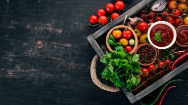 Ürün yelpazesine domates sosları mezarda. Ketçap. Kiraz domates, baharat, biber, zeytin yağı, maydanoz. Üstten görünüm.