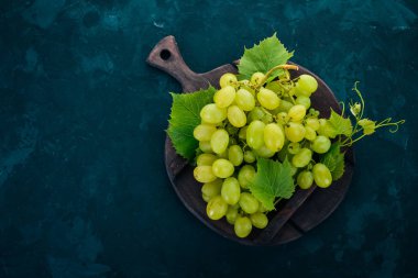 Yeşil üzüm üzüm yaprakları taş bir tablo ile. Üstten görünüm. Metin için boş alan.