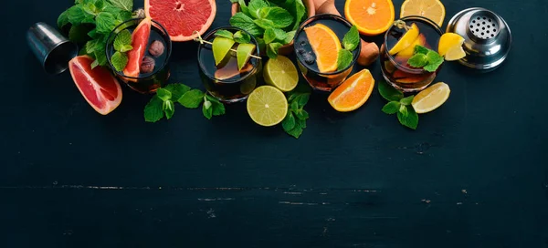 Cocktails with citrus fruit and mint. Lemon, grapefruit, lime, orange. On a wooden background. Top view.