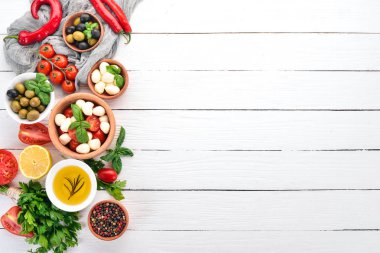 Mozzarella peyniri, domates, fesleğen yaprağı, yağ, zeytin, biber. Beyaz ahşap bir masa üzerinde caprese salatası. Metin için boş alan.