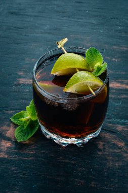 Cuba libre kokteyl cam. Limon, nane. Siyah ahşap arka plan üzerinde. Metin için boş alan.