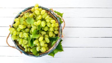Beyaz üzüm mezarda bir beyaz tahta masada. Üzüm yaprakları. Üstten görünüm. Metin için boş alan.