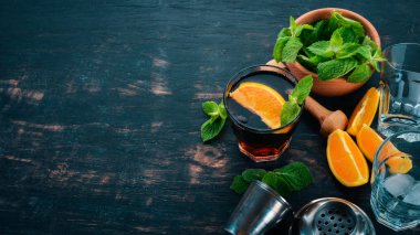 Portakal ve nane ile alkollü kokteyl. Negroni, Long Island, rom-kola. Siyah ahşap arka plan üzerinde. Metin için boş alan.