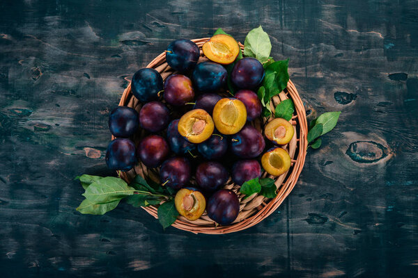 Свежие сливы с листьями. Фрукты На черном деревянном фоне. Вид сверху. Свободное место для текста
.