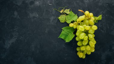 Yeşil üzüm üzüm yaprakları taş bir tablo ile. Üstten görünüm. Metin için boş alan.