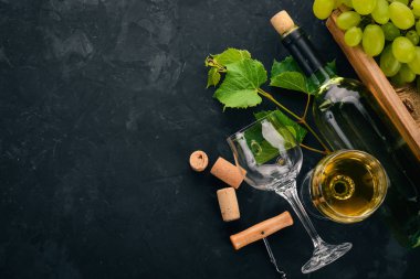 Bir şişe şarap gözlük ve üzüm. Üzüm yaprakları. Üstten görünüm. Siyah taş arka plan üzerinde. Metin için boş alan.