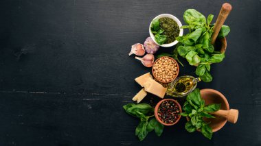 Fesleğen pesto sosu hazırlarken. Fesleğen, parmesan peyniri, zeytinyağı. Üstten görünüm. Siyah ahşap arka plan üzerinde. Metin için boş alan.