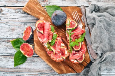 Bruschetta prosciutto, taze incir ve peynir ile. Eski arka plan üzerinde. Sağlıklı gıda. Metin için özgür yer. Üstten görünüm.