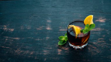 Viski, limon ve nane alkollü kokteyl. Rom-kola. Brandy. Siyah ahşap arka plan üzerinde. Metin için boş alan.