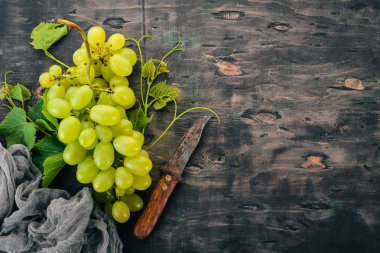 Taze yeşil üzüm üzüm yaprakları ile. Üstten görünüm. Siyah ahşap arka plan üzerinde. Metin için boş alan.