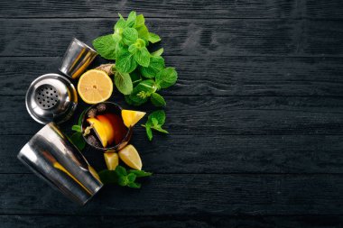 Viski, limon ve nane alkollü kokteyl. Rom-kola. Brandy. Siyah ahşap arka plan üzerinde. Metin için boş alan.