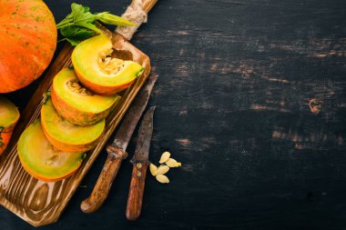 Kabak dilimleri ile ahşap bir gemide kesti. Taze sebze. Siyah bir arka plan üzerinde. Metin için özgür yer. Üstten görünüm.