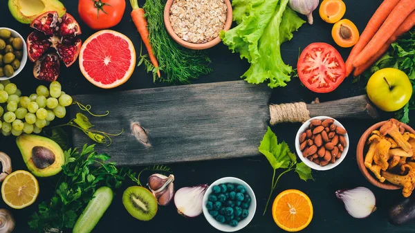 Healthy food clean eating selection: Vegetables, fruits, nuts, berries and mushrooms, parsley, spices. On a black background. Free space for text.