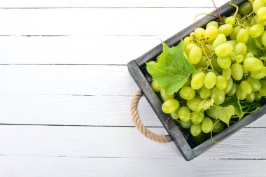 Beyaz üzüm mezarda bir beyaz tahta masada. Üzüm yaprakları. Üstten görünüm. Metin için boş alan.