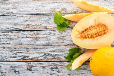 Kavun. Kavun parçalara dilimlenmiş. Beyaz ahşap zemin üzerinde. Metin için özgür yer. Üstten görünüm.