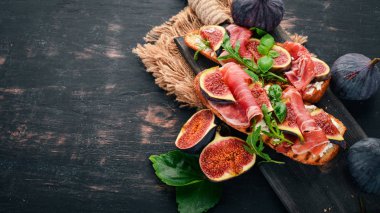 Bruschetta prosciutto, taze incir ve peynir ile. Eski arka plan üzerinde. Sağlıklı gıda. Metin için özgür yer. Üstten görünüm.