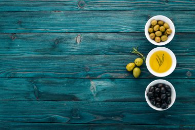 Zeytin ve zeytin yağı ve biberiye kümesi. Yeşil zeytin ve zeytin. Mavi ahşap arka plan üzerinde. Metin için boş alan.